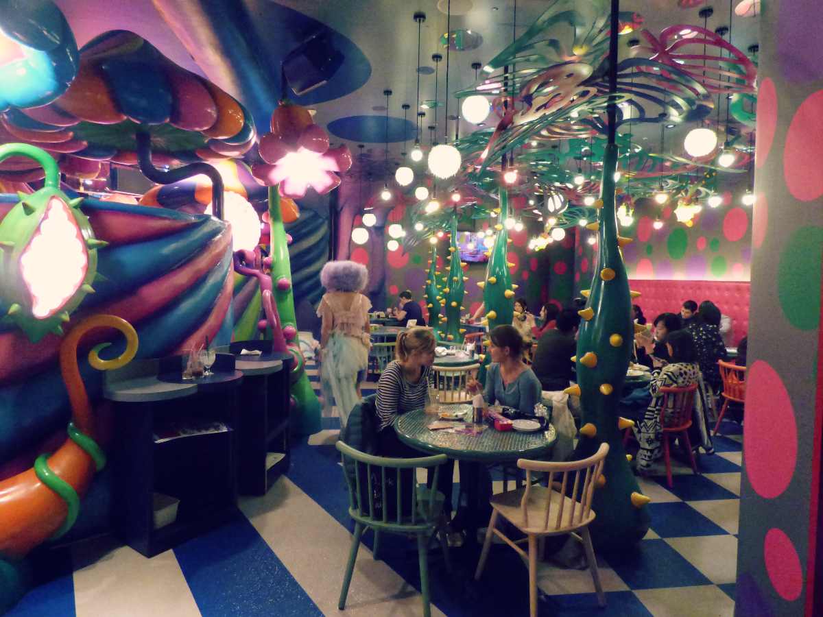 Ihmisiä istumassa värikkäästi koristellussa Kawaii Monster Cafessa Tokiossa.