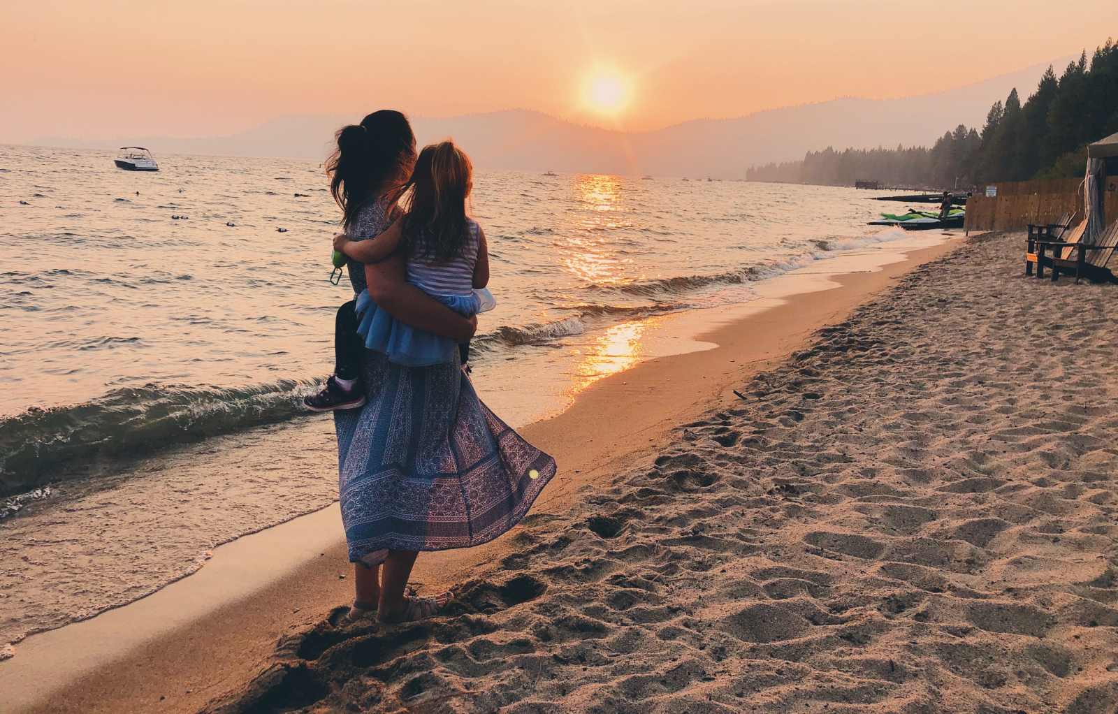 Blogger Paula holding a child on a sunset at Lake Tahoe, California