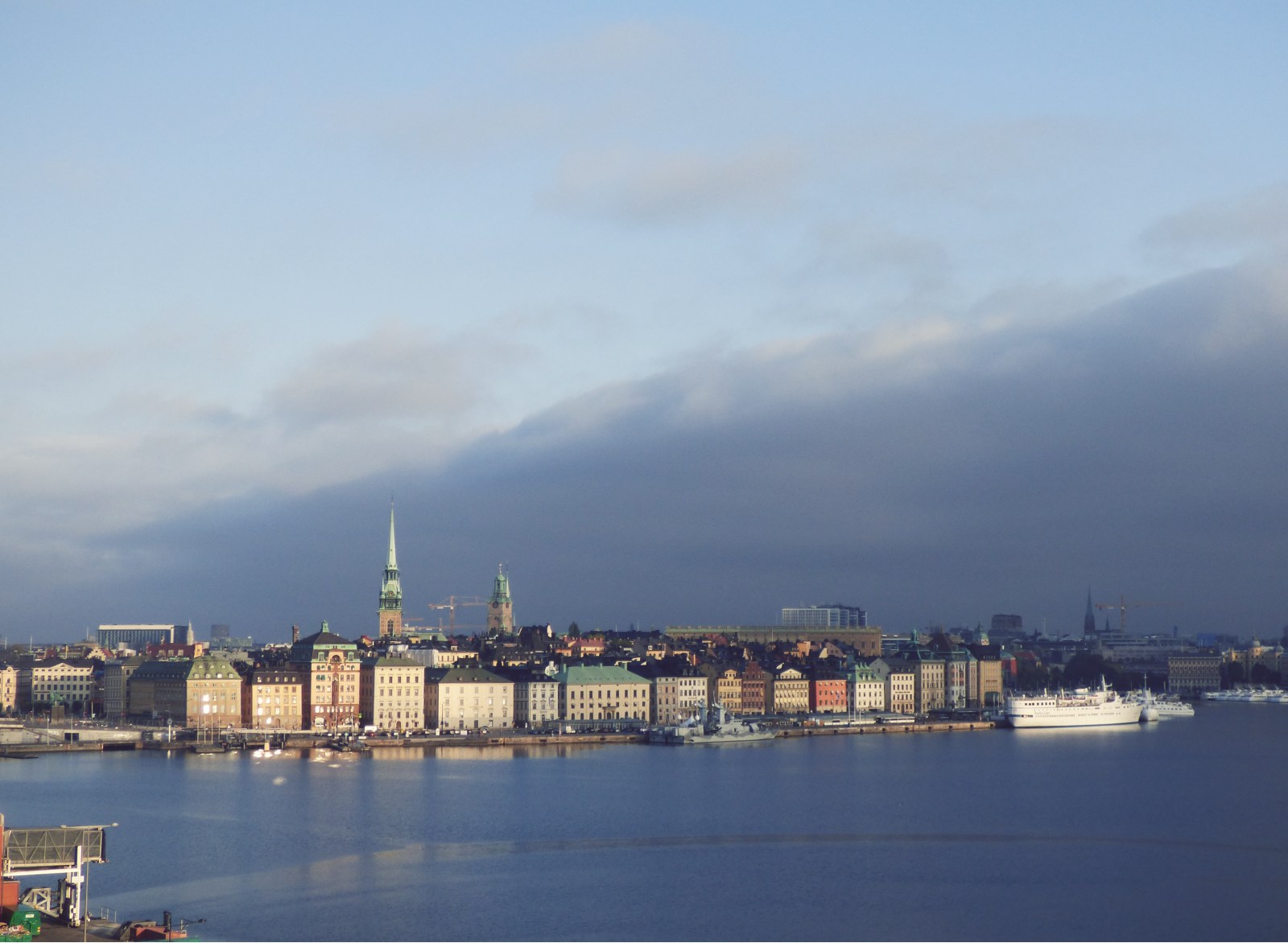The city of Stockholm with some ferries in front of it as seen from the ocean.
