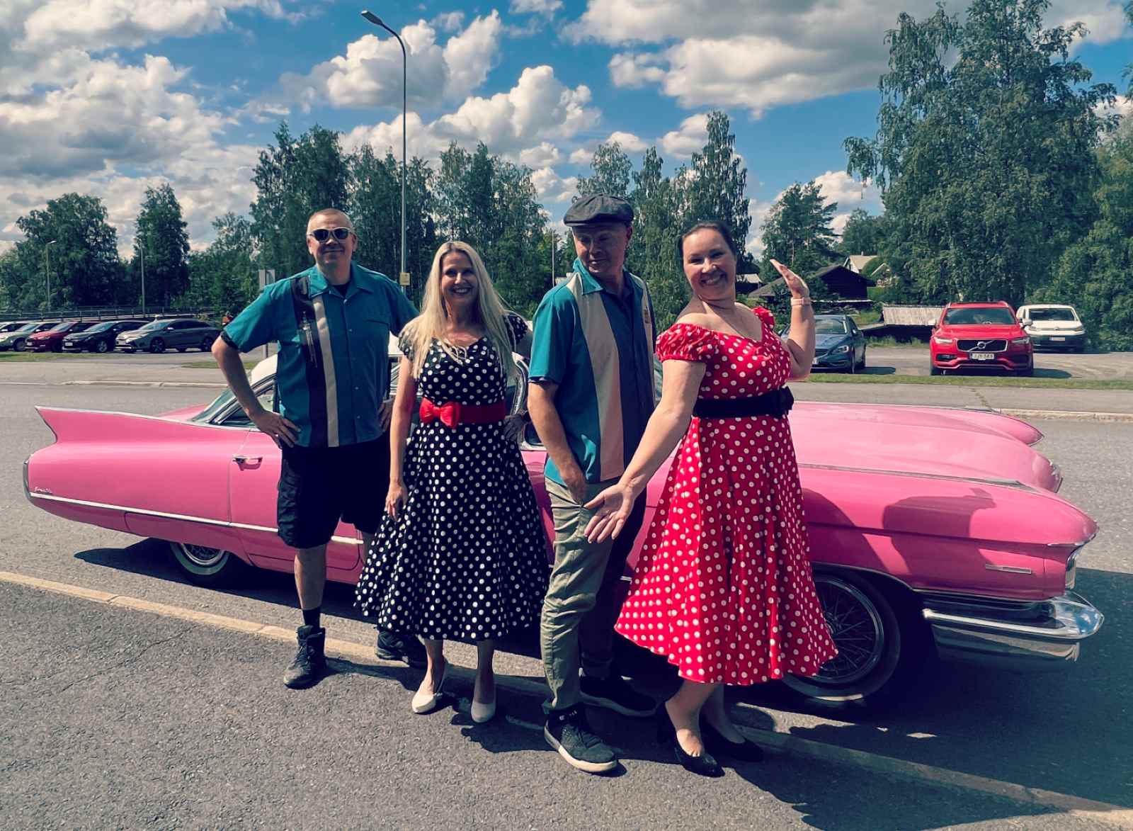 Matkabloggaajat Muotiputiikki Helmen vaatteissa vaaleanpunaisen Cadillacin edessä.